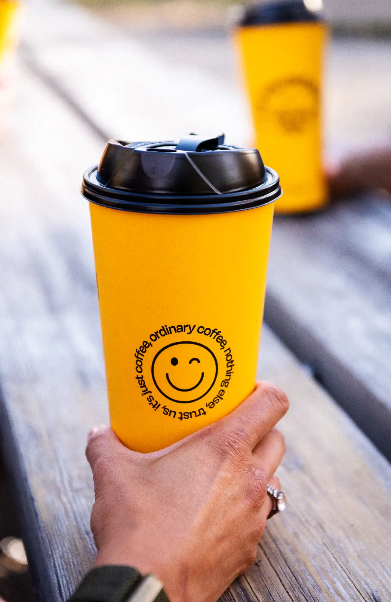 PErson holding Brewsters cup on a picnic table