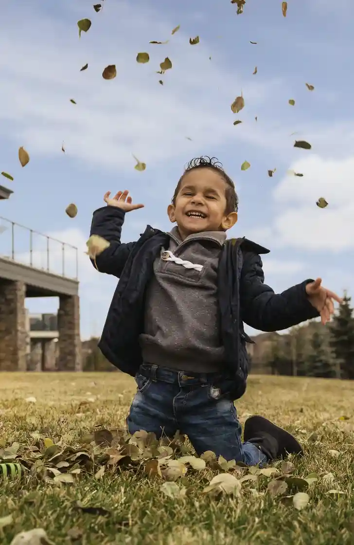 kid playing in leaves